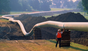 Worker checking welds on natural gas pipeline running through field