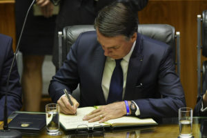 Brazil's President-elect Jair Bolsonaro signs a document at the Congress before he is sworn in as Brazil's new president, in Brasilia on January 1, 2019. - Bolsonaro takes office with promises to radically change the path taken by Latin America's biggest country by trashing decades of centre-left policies. (Photo by NELSON ALMEIDA / AFP)
