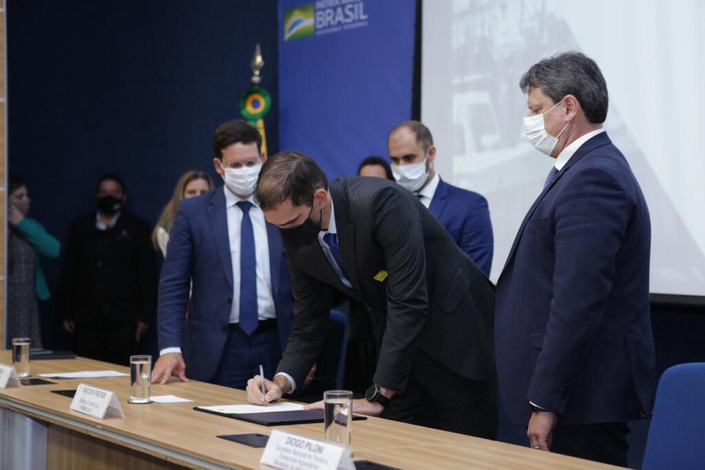 Presidente do Enseada, Mauricio de Almeida, assina documento ao lado do Ministro Tarcísio de Freitas